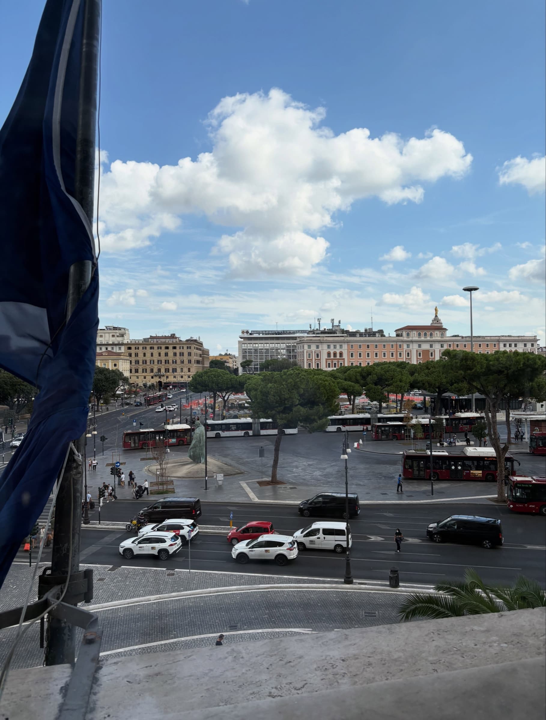 White clouds over a wide square with parked cars